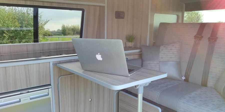 Writing on a laptop beside a camper van